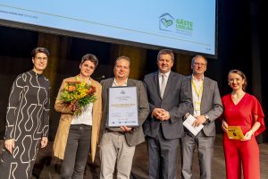 Groep mensen ontvangt uitmuntendheid award op evenement.